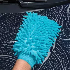 Guante de microfibra azul utilizado para limpiar superficies, con textura suave y diseño ergonómico.