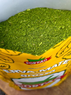 Pacote de erva-mate grossa com rótulo amarelo da marca Portão, mostrando a parte superior aberta mostrando o conteúdo bem verde.