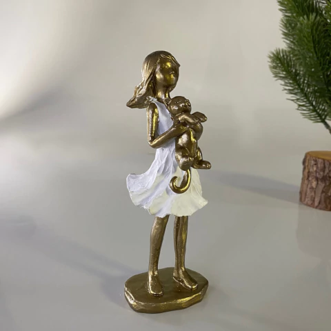 Escultura decorativa de menina dourada segurando um gato, com vestido branco, medindo 16 cm