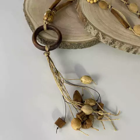 Colar de mesa rústico decorativo com canela, sementes naturais e cordas entrelaçadas em fundo branco com base de madeira