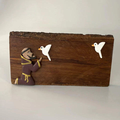 Quadro de São Francisco de Assis em madeira com figuras de pássaros, medindo 22x12 cm.