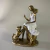 Escultura decorativa de moça sentada com vestido branco e cachorro ao lado, ambos em acabamento dourado e branco, medindo 17 cm