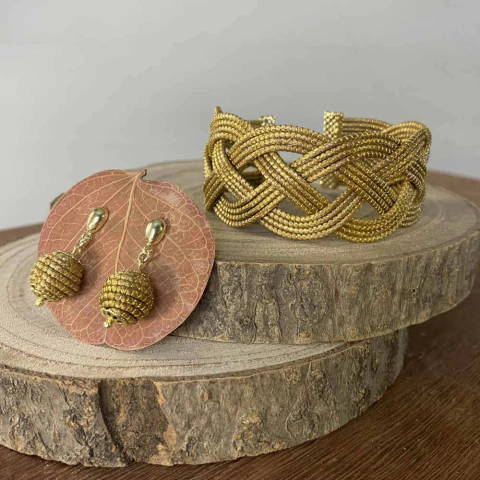 Conjunto artesanal de pulseira e brinco feito com capim dourado, exibido sobre base de madeira rústica