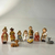 Conjunto de figuras representando o nascimento de Jesus, incluindo personagens como Maria, José, pastores e animais.