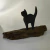 Escultura rústica de gatinho preto em madeira sobre base de madeira natural