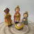 Três figuras de reis magos com coroa, segurando presentes, ao lado do menino Jesus em um berço.