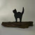 Escultura rústica de gatinho preto em madeira sobre pedaço de madeira natural