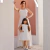 Mulher e menina vestindo vestidos longos off white combinando no estilo Tal Mãe Tal Filha, posando em ambiente com paredes claras