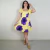 Mulher vestindo vestido amarelo curto com estampa de flores roxas, com mangas curtas e saia rodada