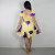Mulher vista por trás usando vestido amarelo curto com estampa de flores roxas, modelo com decote quadrado e mangas curtas bufantes