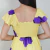 Vestido amarelo com estampa de flores roxas, detalhe franzido na parte superior e mangas curtas, visto de costas