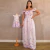 Mulher vestindo vestido longo branco com estampa de borboletas coloridas ao lado de manequim com vestido infantil combinando