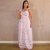 Mulher vestindo vestido longo branco com estampa de borboletas em tons de rosa e lilás, com alças de babado