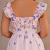 Vestido longo feminino com estampa de borboletas em tons de rosa e roxo, visto de costas, com mangas curtas bufantes e fechamento por zíper