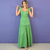 Mulher vestindo vestido longo verde oliva com alças largas e babados, em fundo roxo