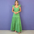 Mulher vestindo vestido mídi verde oliva com babados nos ombros, em fundo roxo