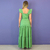 Mulher vestindo vestido longo verde oliva com babados nos ombros, vista de costas