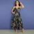 Mulher vestindo vestido midi feminino Iana Abacaxi com estampa floral em fundo preto, com alças finas e saia rodada