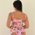 Mulher vista de costas usando vestido longo rosa com estampa floral em tons de rosa, marrom e verde