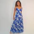 Mulher usando vestido longo Giovana Max com estampa floral azul e branco, alças finas e saia rodada