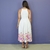 Vestido branco midi com estampa floral colorida na barra, visto por trás
