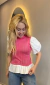 Mulher vestindo blusa rosa de tricot com mangas princesa brancas e barra plissada em tricoline branca, combinada com jeans azul claro
