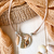 Collar femenino Aloha en tonos beige con un dije redondo de vidrio y detalles plateados