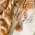 Collar de piedras, cerámica y metal con dije handmade en color naranja