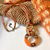 Collar en tendencia largo en color marron y camel, con cordon de algodon y detalles metalicos en color bronce