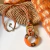 Collar en tendencia largo en color marron y camel, con cordon de algodon y detalles metalicos en color bronce
