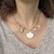 Collar corto de cadena con dijes de estrella de mar, caracoles y perla.
