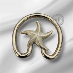 Fivela modelo estrela em ABS dourado, com detalhe de estrela do mar, apresentada sobre um fundo claro.