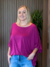 Mulher usando a Blusa Gabi Lisa de cor violeta, com calça jeans, em ambiente interno.
