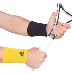 Muñequeras de tenis adidas en colores negro y amarillo, utilizadas durante un partido de tenis.