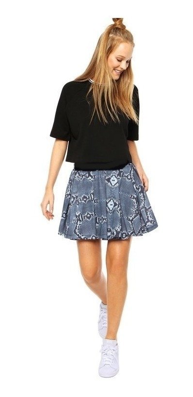 Modelo usando una pollera mini falda de estampado urbano en tonos azul y blanco, combinada con una camiseta negra y zapatillas blancas.