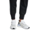 Zapatillas adidas Futurepacer blancas con detalles en negro y azul, vistas desde el costado, usadas con pantalones deportivos negros.