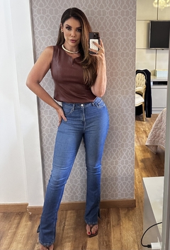 Modelo usando calça Jordana boot cut hot pants em jeans azul, com blusa marrom e acessórios elegantes.