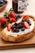 Torrada com creme branco, geleia de frutas vermelhas da Provençal Gourmet, morangos e mirtilos em prato de madeira