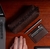 Estojo de couro marrom, uma caneta prateada próximo a um laptop.
