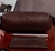 Estojo de couro marrom da marca Pellibrasil, com caneta prateada e um porta-cartões de couro ao lado, sobre uma mesa de madeira.