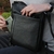 homem guardando celular no bolso externo da bolsa tiracolo de couro haneda preto
