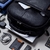 Mochila de couro masculina Pelli Brasil em couro preto, vista de frente sobre uma mesa com objetos em seu interior