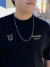 Jovem usando uma camiseta preta e óculos, com uma corrente prata 925 pendurada no pescoço, em um ambiente urbano colorido.