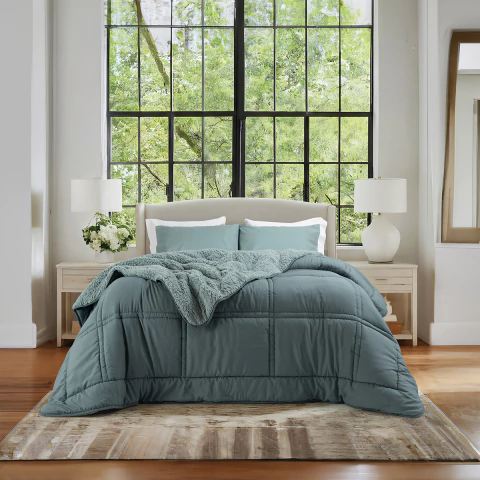 Acolchado reversible con corderito color celeste L Sense Dúo de 1 1/2 plaza sobre cama, en dormitorio luminoso y moderno.