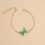 Pulsera delicada de cadena dorada con dije central en forma de mariposa con cristales tornasol verdes y azules