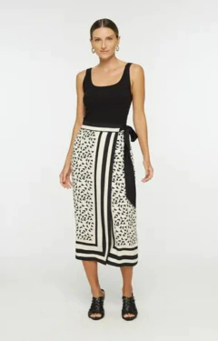Modelo vestindo uma saia pareo da marca Animale, com estampa geométrica em preto e branco, combinada com uma blusa preta.