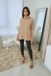 Modelo vestindo uma blusa de gola alta Ambicione por Anselmi na cor cappuccino, combinada com calças de couro pretas, em um ambiente moderno e iluminado.