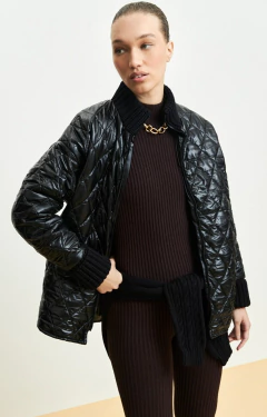 Jaqueta Feminina Ambicione por Anselmi Matelassê preta, com detalhes em matelassê, usada por uma modelo em ambiente neutro.