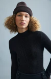 Modelo usando blusa preta Ambicione com padrão de ponto chevron e gorro marrom, em fundo claro.