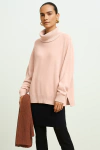 Blusa Ambicione Por Anselmi ampla de gola alta na cor rosé, com detalhes nas mangas, exibida por uma modelo que segura um cachecol.